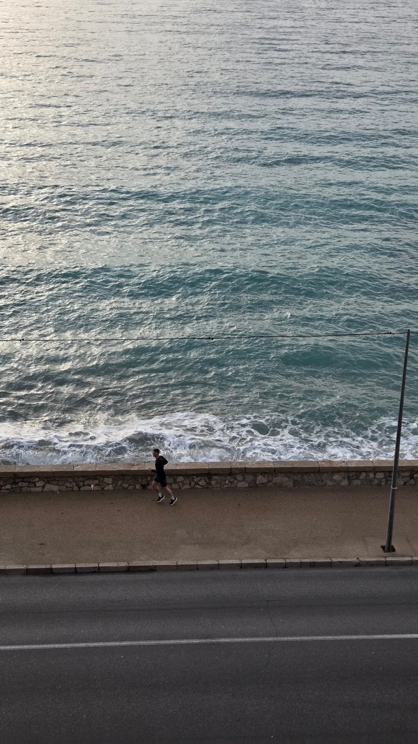 Jogger on the seafront promenade below Best Western Premier Hotel Prince de Galles, Menton