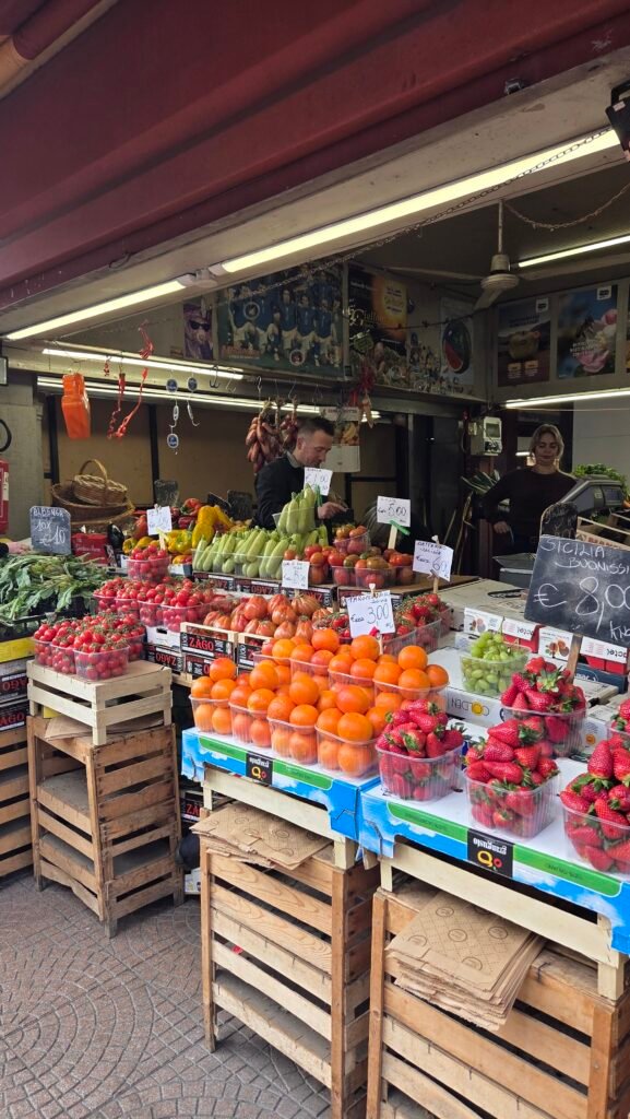 Fresh produce stall with tomatoes, oranges, and strawberries at Mercato Coperto, Ventimiglia