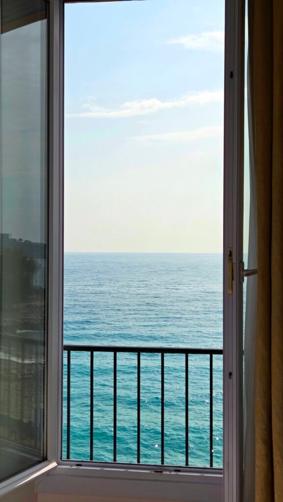 Sea view of the Mediterranean through an open balcony door at Best Western Premier Hotel Prince de Galles, Menton
