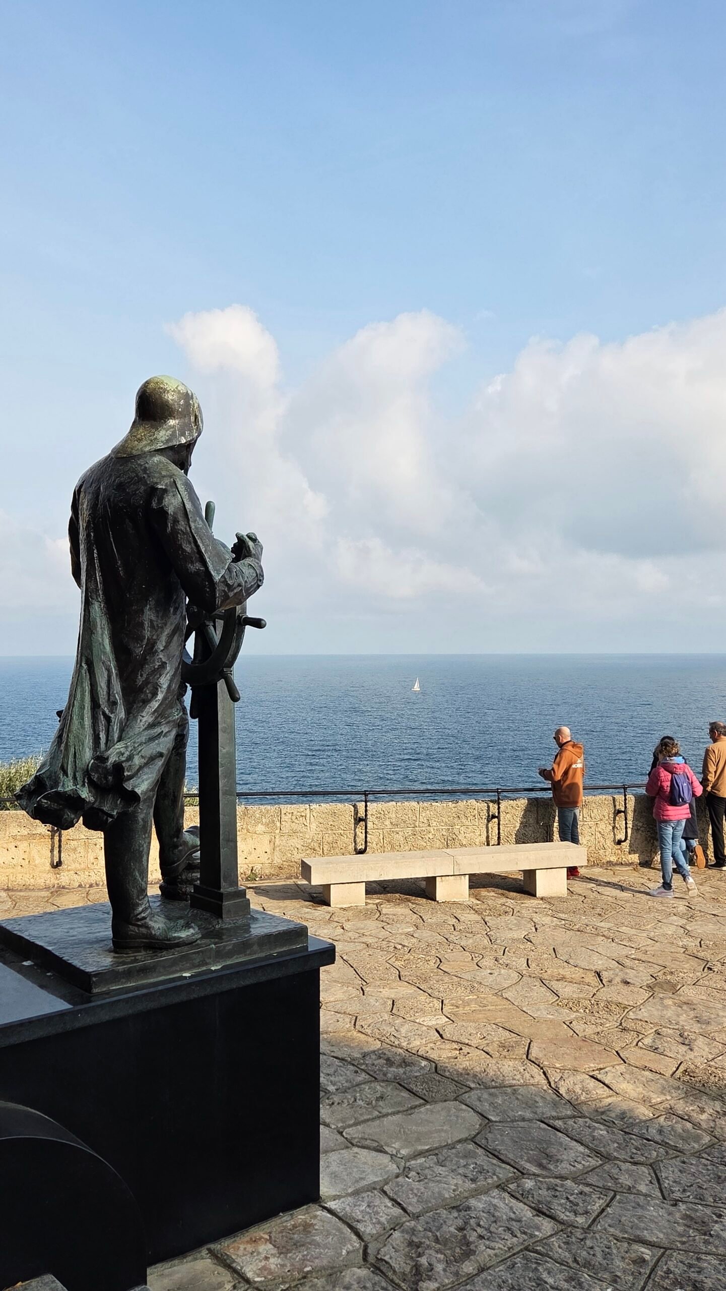 Sailor statue facing the sea with a bench nearby in Monaco