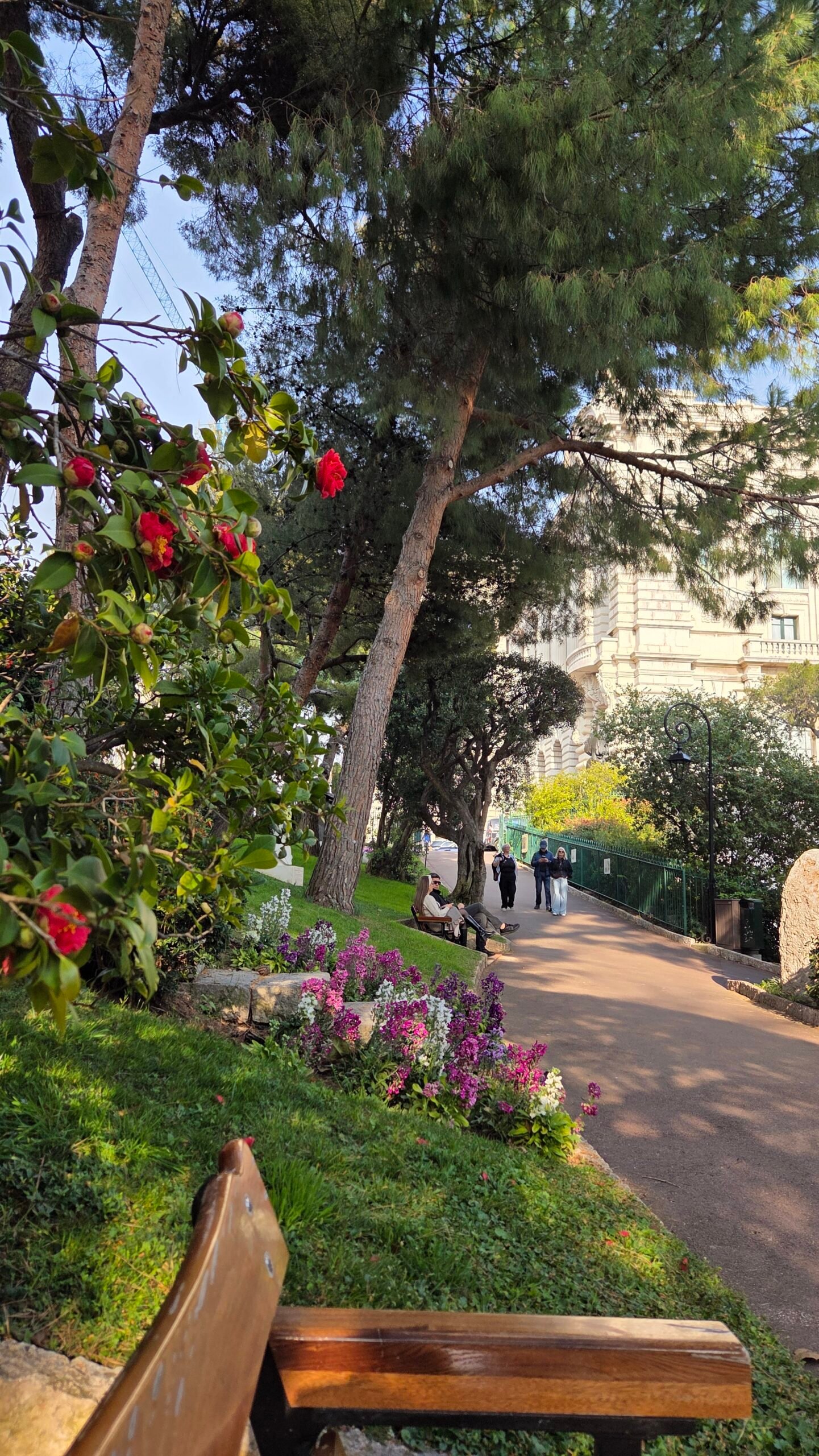 Path through the Jardins Saint-Martin in Monaco lined with spring flowers and benches