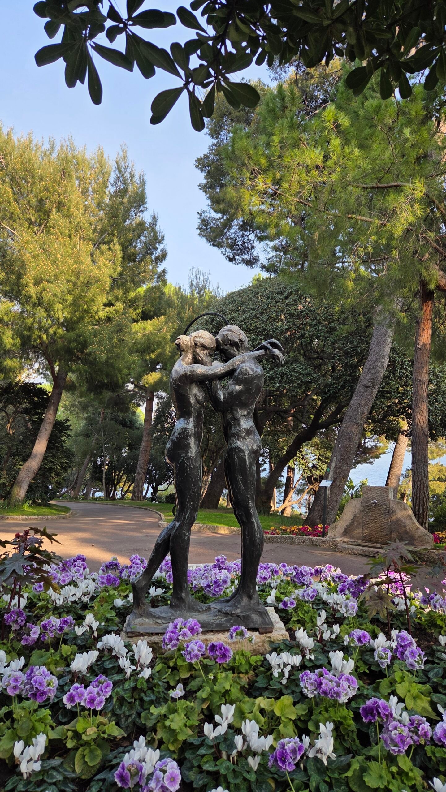 Bronze statue of a couple surrounded by purple flowers in the Jardins Saint-Martin, Monaco