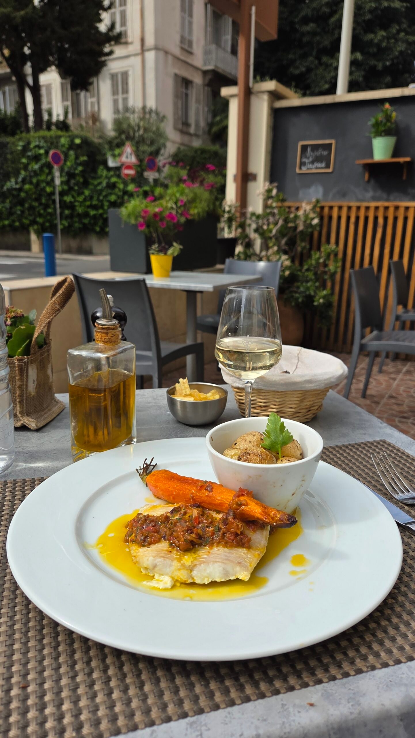 Fish fillet with tapenade, roasted carrot, and potatoes at a Nice restaurant terrace