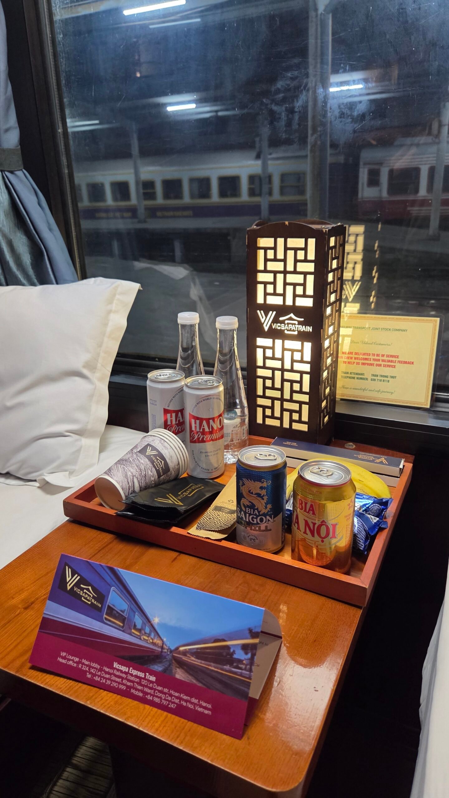 Water, a Hanoi Premium beer, and the VicSapa Train bedside lamp in the sleeper train cabin