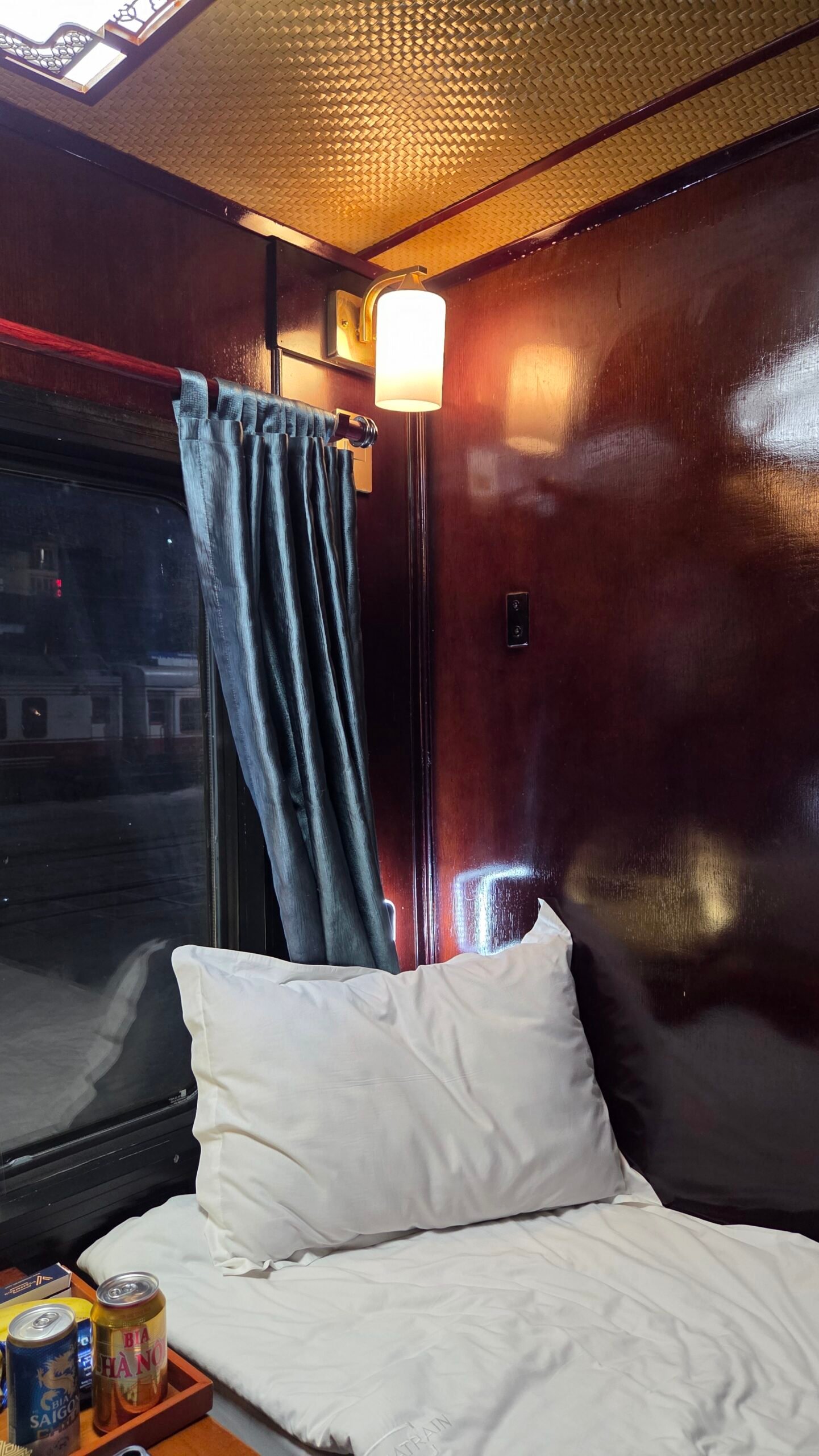 Red wood paneling and the warm reading lamp inside the sleeper train cabin